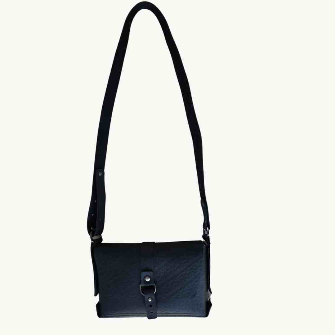 Close-up of the Reina crossbody strap featuring upcycled vegan leather with silver hardware and embossed logo detail