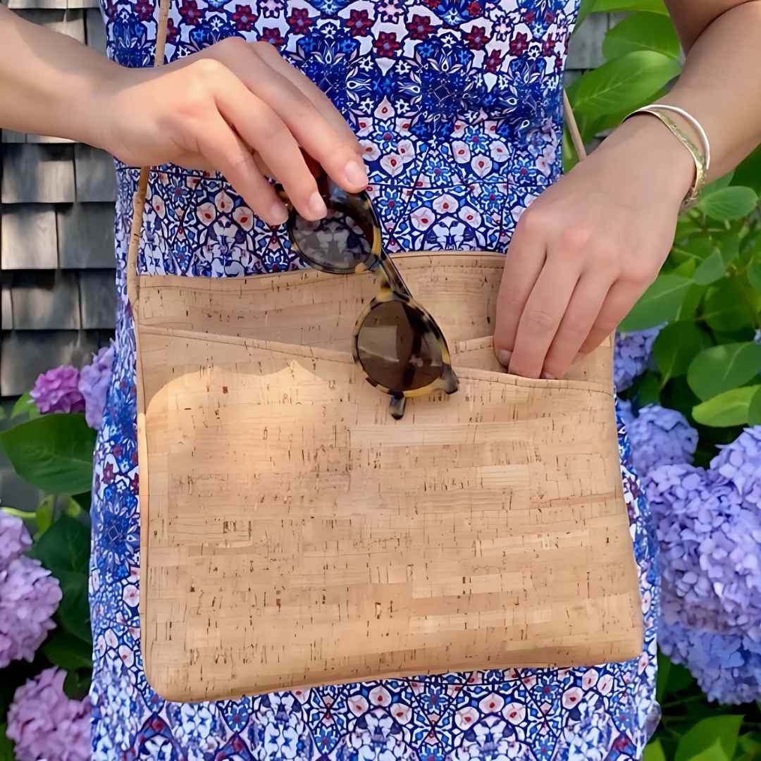 Close-up of the cork vegan crossbody bag’s textured surface and gold-tone metal clasp detail from an overhead angle.