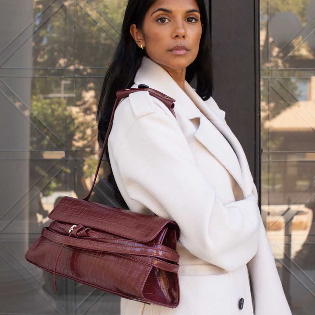 Faux croc vegan leather handbags in burgundy with a woman carrying it