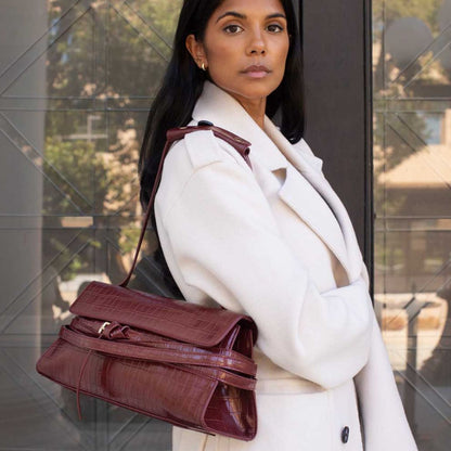 Faux croc vegan leather handbags in burgundy with a woman carrying it