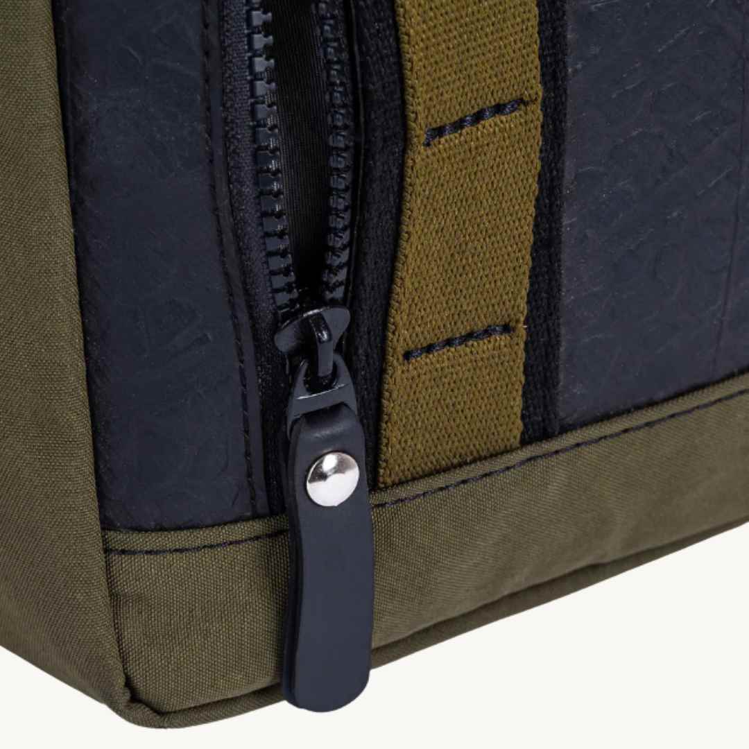 Close-up of a zipper on a bag with green and navy colors.